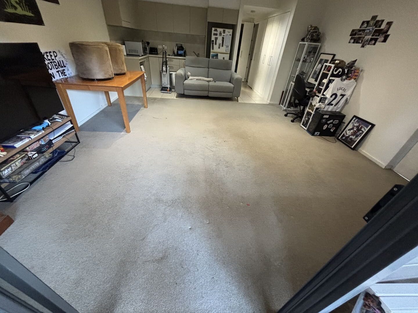 Carpet with noticeable dark stains and marks in a living room setting, highlighting the need for professional cleaning before a rent inspection.